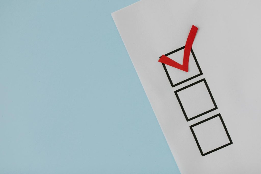 Factors to Consider Before Choosing, A simple white paper checklist with one red checkmark, ideal for concepts like completion or approval.